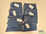 two pairs of blue jeans with tags on them sitting on a table