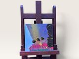 un chevalet miniature sur lequel est posé un tableau