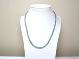 collier composé de perles de verre vertes sur un mannequin blanc