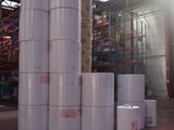 many rolls of white paper stacked up in a warehouse