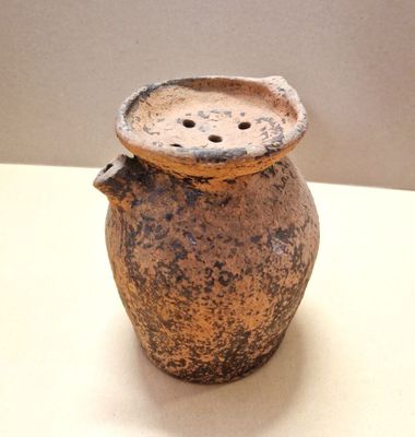a brown vase sitting on a table with a lid