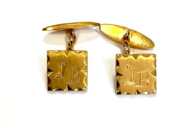 two gold cufflinks with initials on them on a white surface