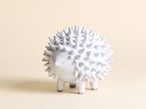 un petit hérisson blanc qui se tient debout sur une table