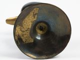 a close up of a black and gold vase on a white surface