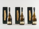 three bottles of champagne are lined up on a white surface