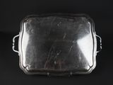 an antique silver plate with handles on a black background