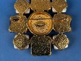 an image of a gold colored broochle with a face on it