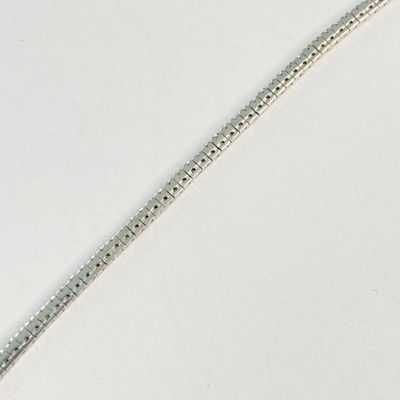 une chaîne en argent posée sur une surface blanche