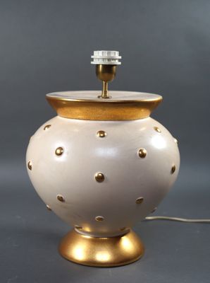 une photo d'une lampe blanche et dorée posée sur une table
