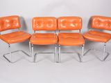 four orange leather chairs are lined up against a white backdrop