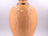 a large orange vase with a leaf design on it
