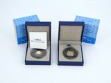 two gold coins in a blue box on a white surface