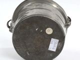 a metal bucket with a tag on it sitting on a white surface