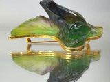 une broche en forme d'oiseau vert et noir sur une plaque en or
