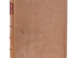 un vieux livre à la couverture brune posé sur une surface blanche