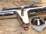 a close up of a metal pipe and fittings on a piece of plywood