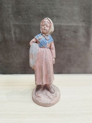 figurine représentant une femme avec un panier, posée sur une table en bois