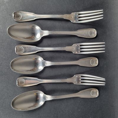 six fourchettes et cuillères sont alignées sur une surface noire