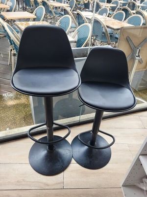 une paire de tabourets de bar en cuir noir devant une grande fenêtre