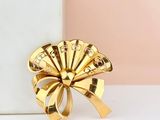 gold plated ring with a fan shaped design on top of a white box