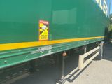 a green semi truck with a yellow stripe on the side of it