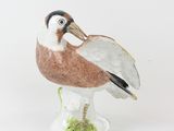 porcelain figurine of a bird on a pedestal on a white background