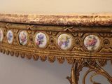 a gold table with a marble top and flowers on it
