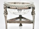 an antique silver plate with a bowl on a stand on a white surface