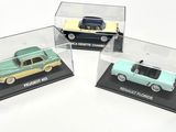 trois voitures miniatures dans une vitrine posée sur une surface blanche