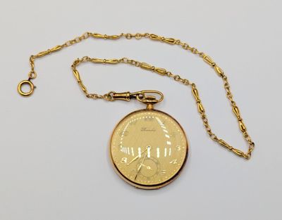 a gold pocket watch with a chain on a white surface