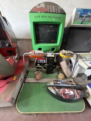 a green arcade machine sitting on top of a green mat