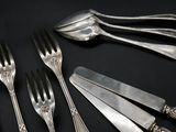 several forks and spoons are arranged in a circle on a black surface