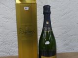 une bouteille de champagne posée à côté d'un coffret en or sur une table en bois