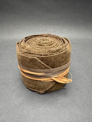 un gros plan sur un rouleau de tissu marron posé sur une surface grise