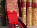 une boîte rouge ornée d'un ruban rouge et contenant une paire de broches
