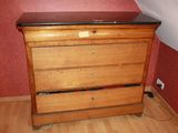 a wooden dresser with a black top in a room