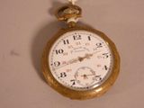 a gold pocket watch hanging on a white wall