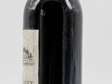 an old bottle of wine sitting on top of a white table