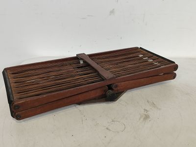 un vieux plateau en bois muni d'une poignée en bois, posé sur une surface blanche