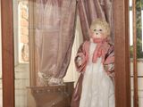 une poupée dans une vitrine, avec un rideau en arrière-plan