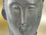 sculpture of a woman ' s head on a table in front of a yellow background