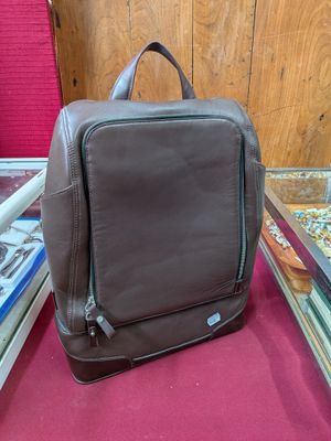 un sac à dos en cuir marron posé sur un tapis rouge devant une vitrine