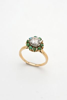a close up of a gold ring with a diamond and emeralds