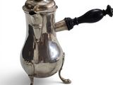 a silver coffee pot with a black handle on a white background