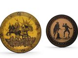 two decorative plates with figures on them sitting next to each other