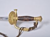 a sword with a gold handle on a white surface