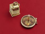 a small gold clock and a small silver clock on a red surface