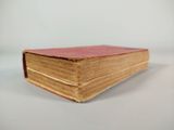 an old book sitting on top of a white table next to a white wall