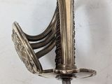 a silver sword with a gold handle on a white wall