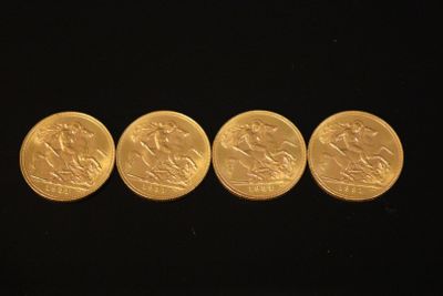 four gold coins sitting side by side on a black surface